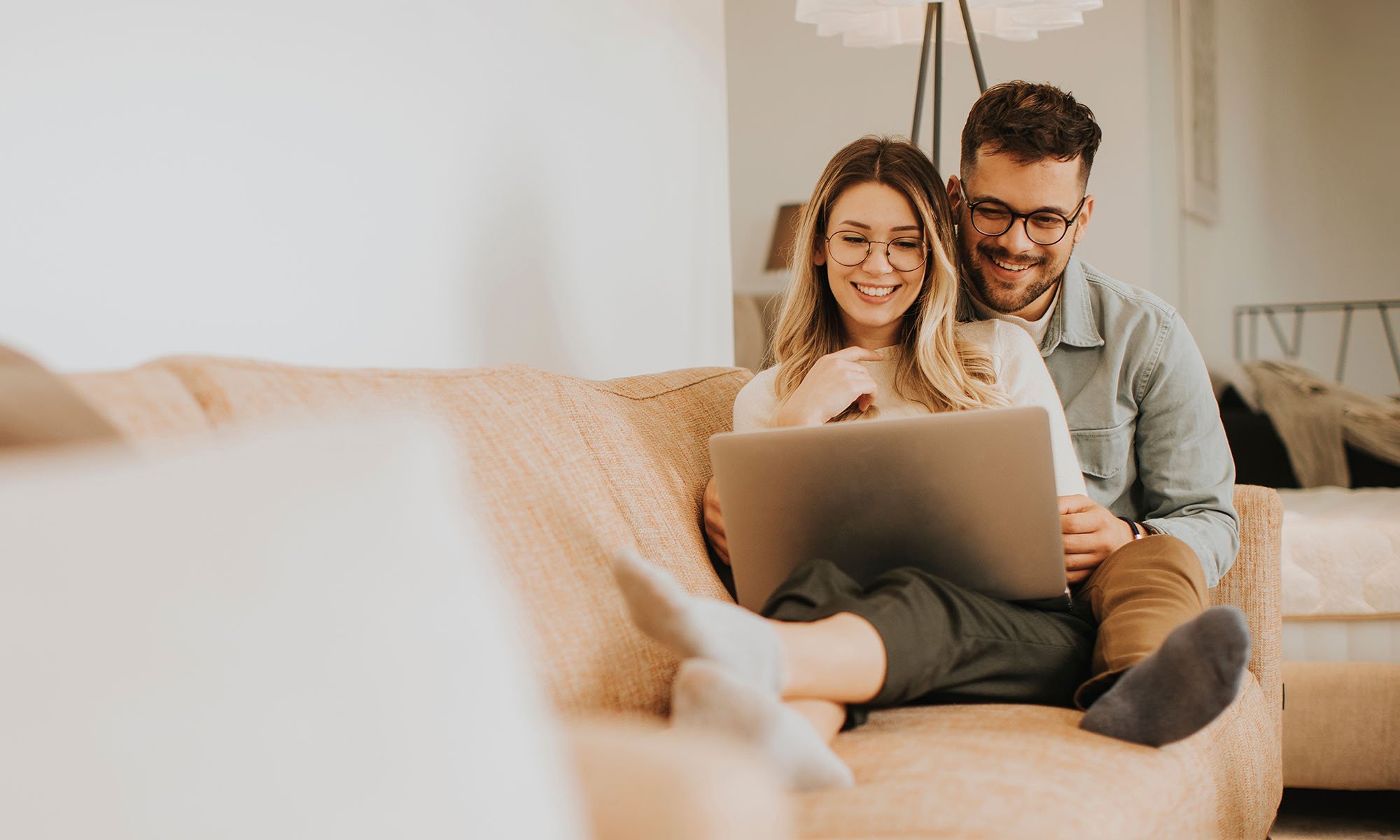 happy couple on couch using laptop
